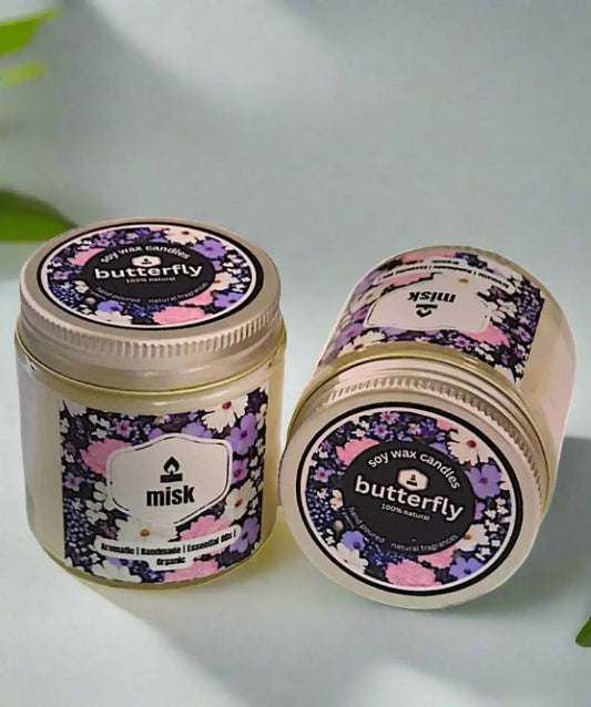 Two 'misk' butterfly-themed candles on a light background
