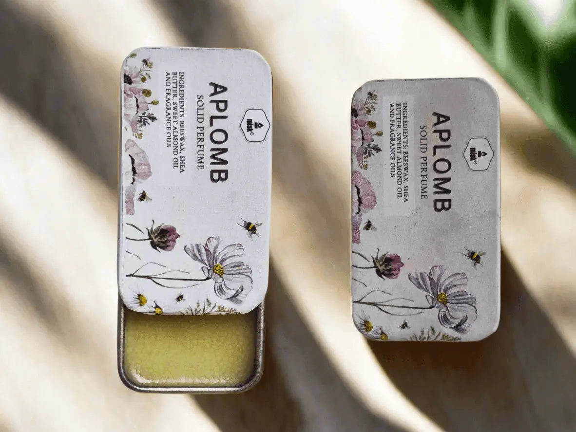 Two Aplomb solid perfume tins on a light background