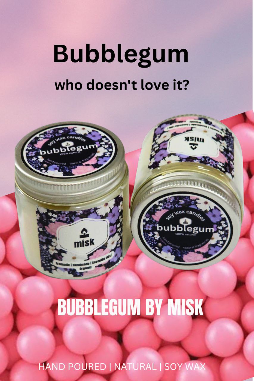 Two misk Bubblegum soy wax candles with floral labels, one upright and one tilted, are displayed against a background of pink bubblegum balls. Text on the image reads: "Bubblegum who doesn't love it?" "BUBBLEGUM BY MISK"
