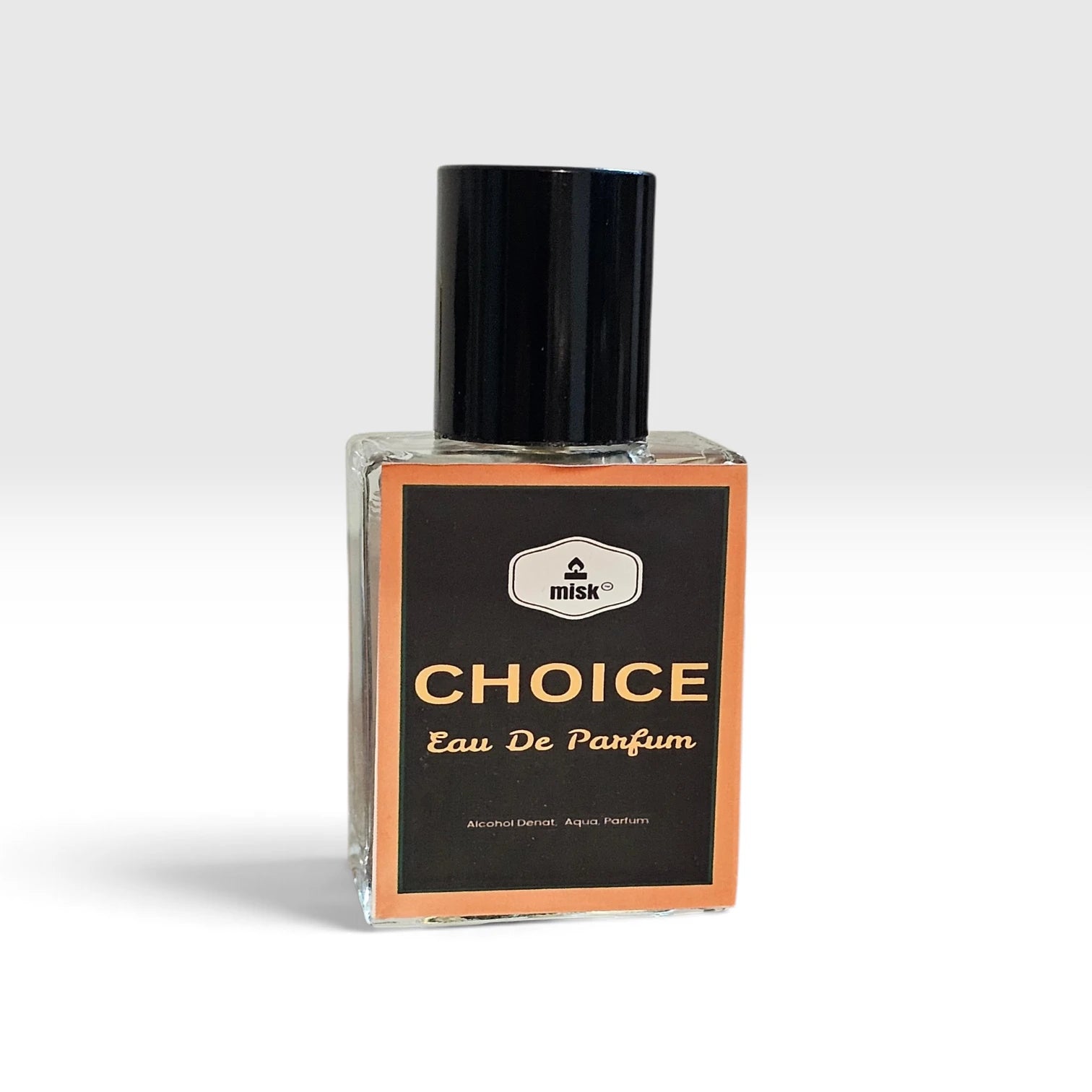A rectangular glass bottle of Misk Choice Eau De Parfum with a black cap and a black label featuring gold lettering and a peach border, set against a light gray background.