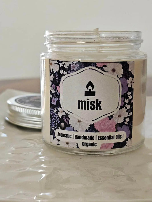 Misk candle jar with floral label on a reflective surface