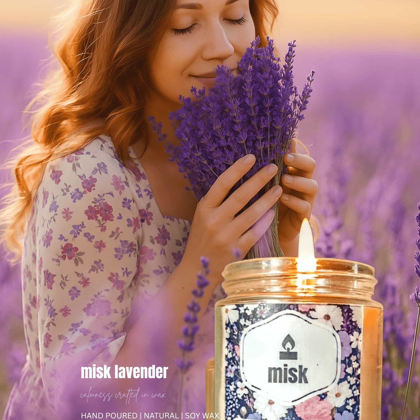 Woman holding lavender flowers next to a lit 'misk lavender' candle in a field of lavender.